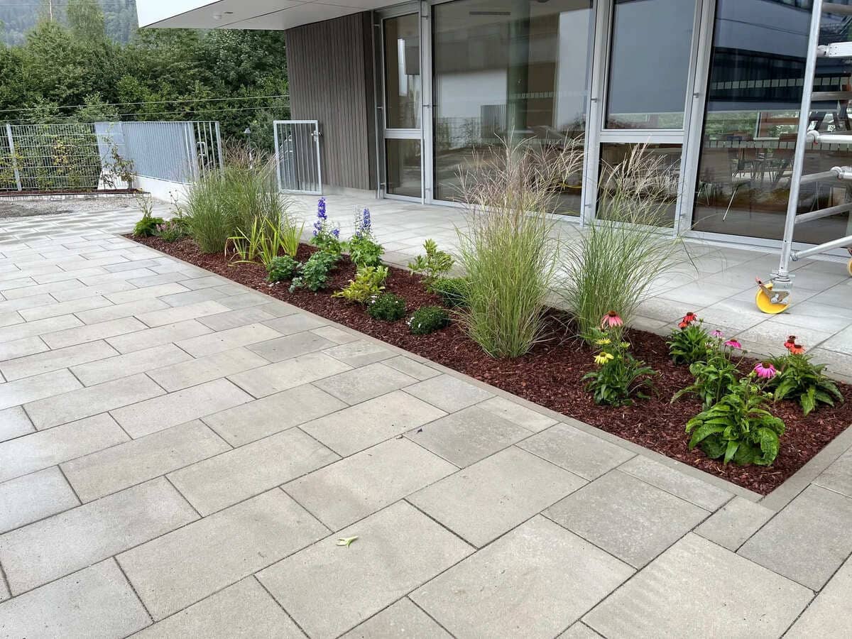 Blumenbeet umgeben von einem modernen gefliesten Boden