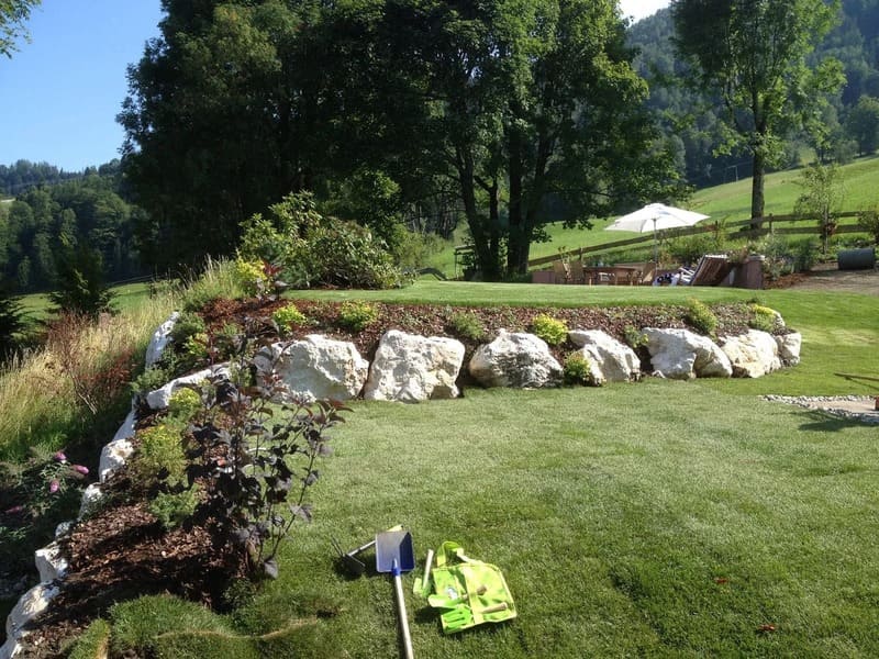 Moderner und strukturierter Garten mit einer grünen Wiese und einer Steinmauer